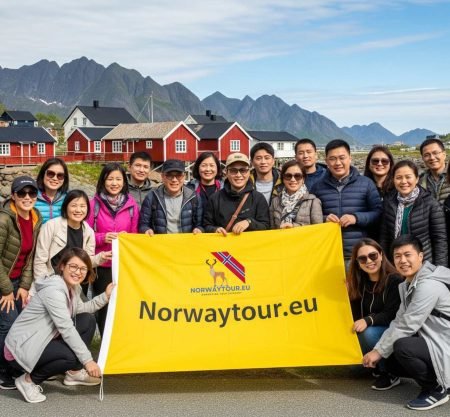 Group of tourists posing with Norwaytour.eu banner in front of red fishing cabins at Hamnøy during Lofoten Islands Photo Tour: Reine, Hamnøy & Skariskøya from Svolvær